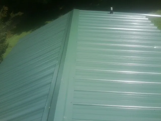 New green metal panels meeting at the ridge of a roof — Flat Roof Repair work by our crew in Branson