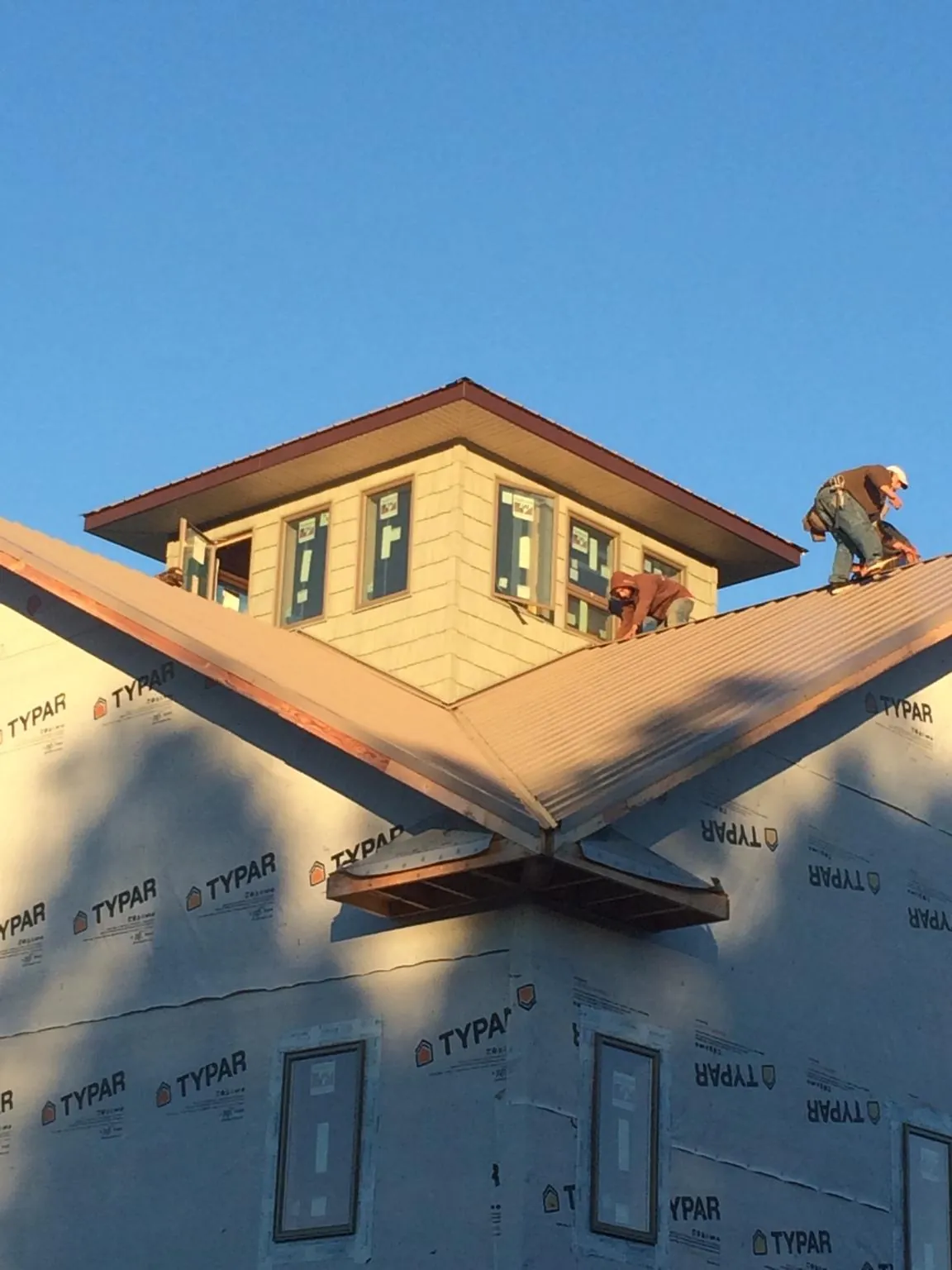 Roofers working around a rooftop cupola on a new metal roof at sunset — Roof Waterproofing in Branson by Roofing Brothers